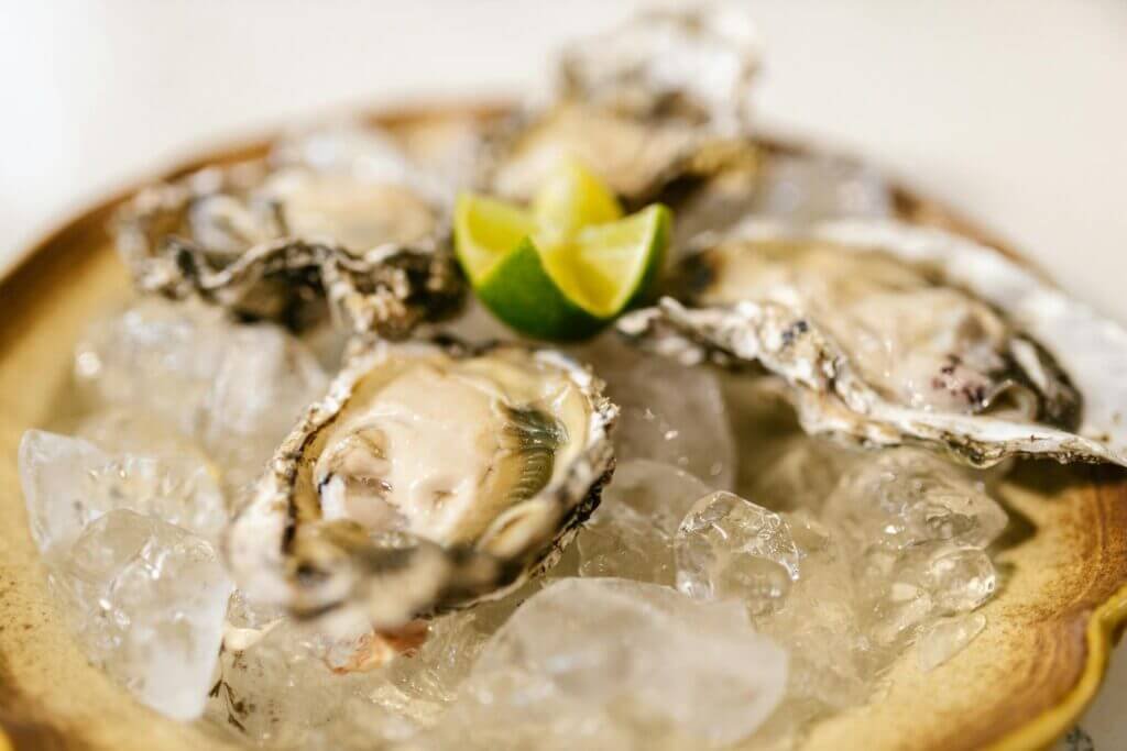 Close-up of fresh oysters served on ice with a lime wedge.